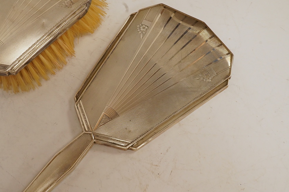 A cased George VI Art Deco silver mounted silver four piece mirror, brush and comb set, Charles S. Green & Co, Birmingham, 1948-1952. Condition - poor to fair to good.